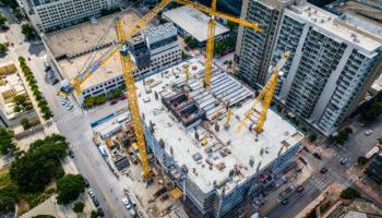 An Image Of A Dense Urban Construction Site With Several Cranes Visible.